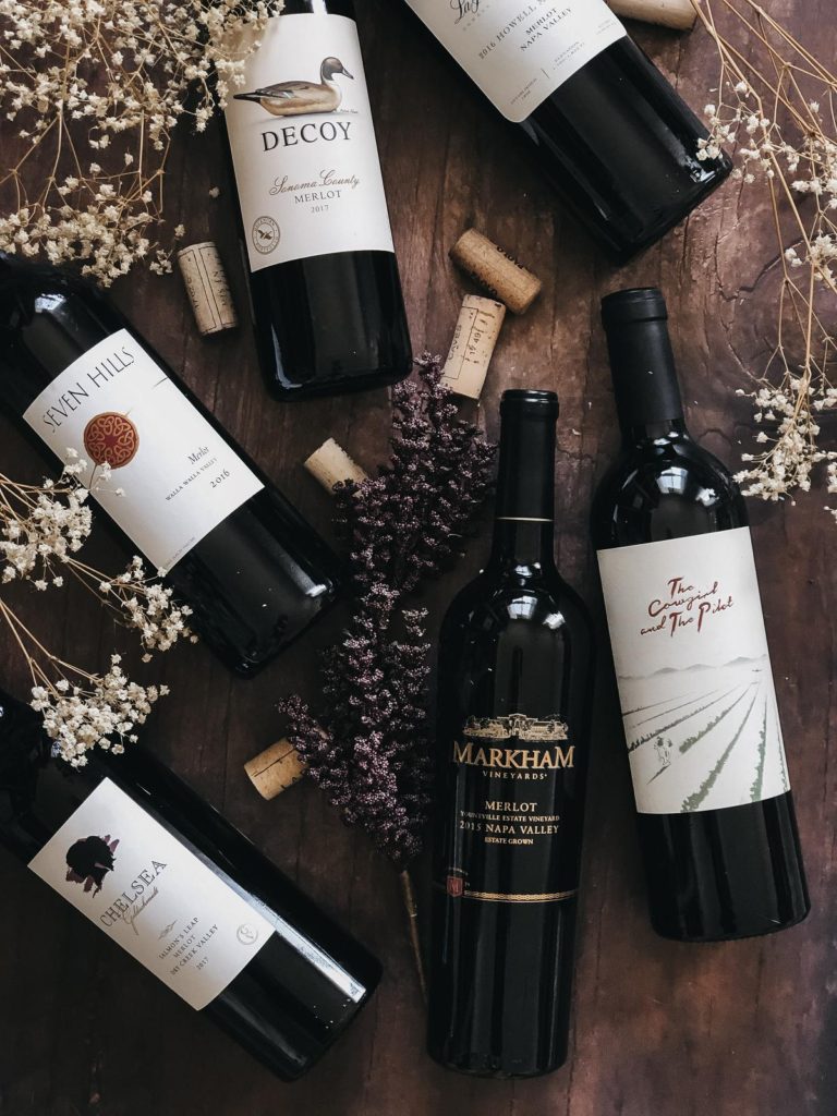 bottles of merlot wines on a table with wine corks