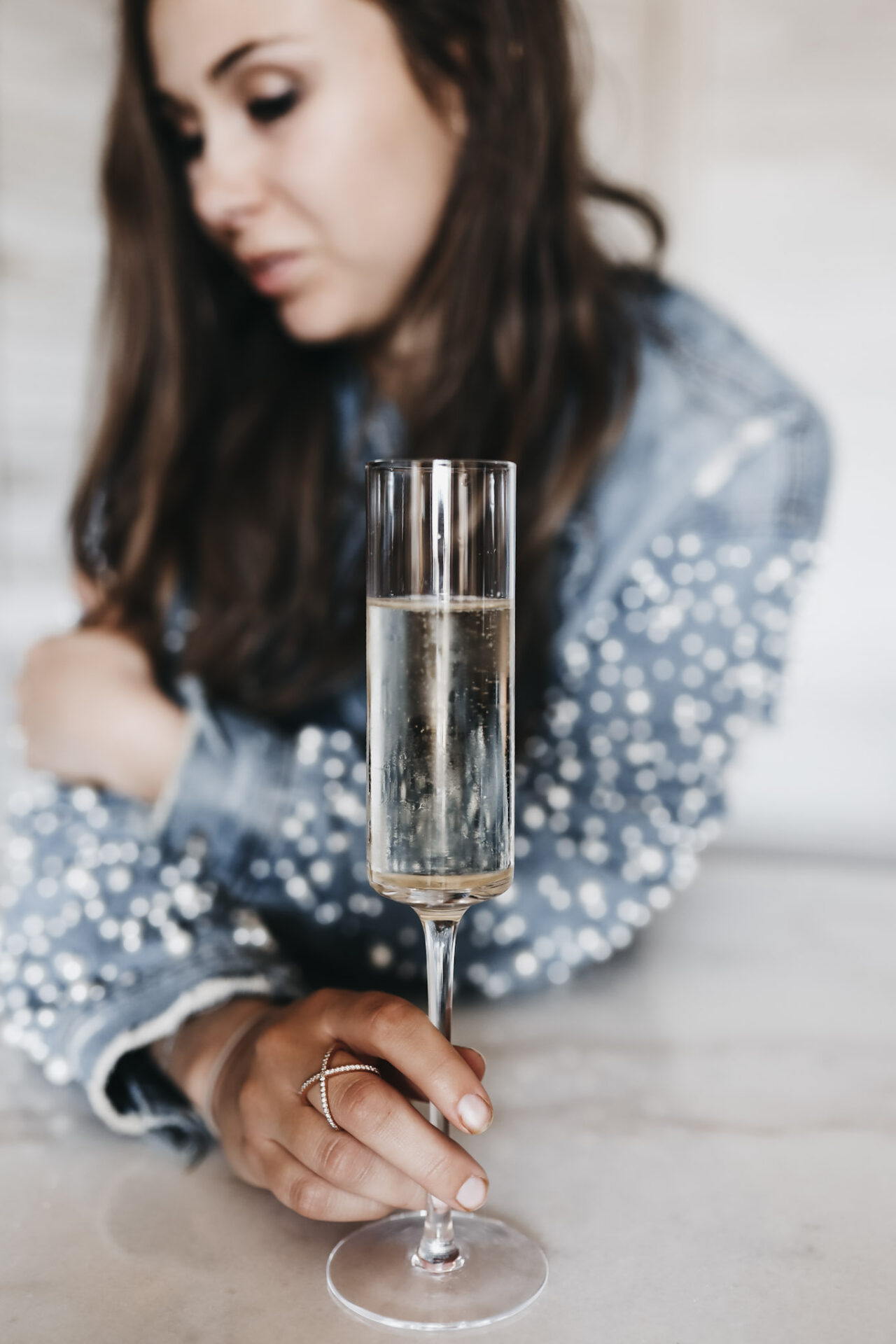 Girl holding a glass of champagne wearing an amazing jean jacket with pearls
