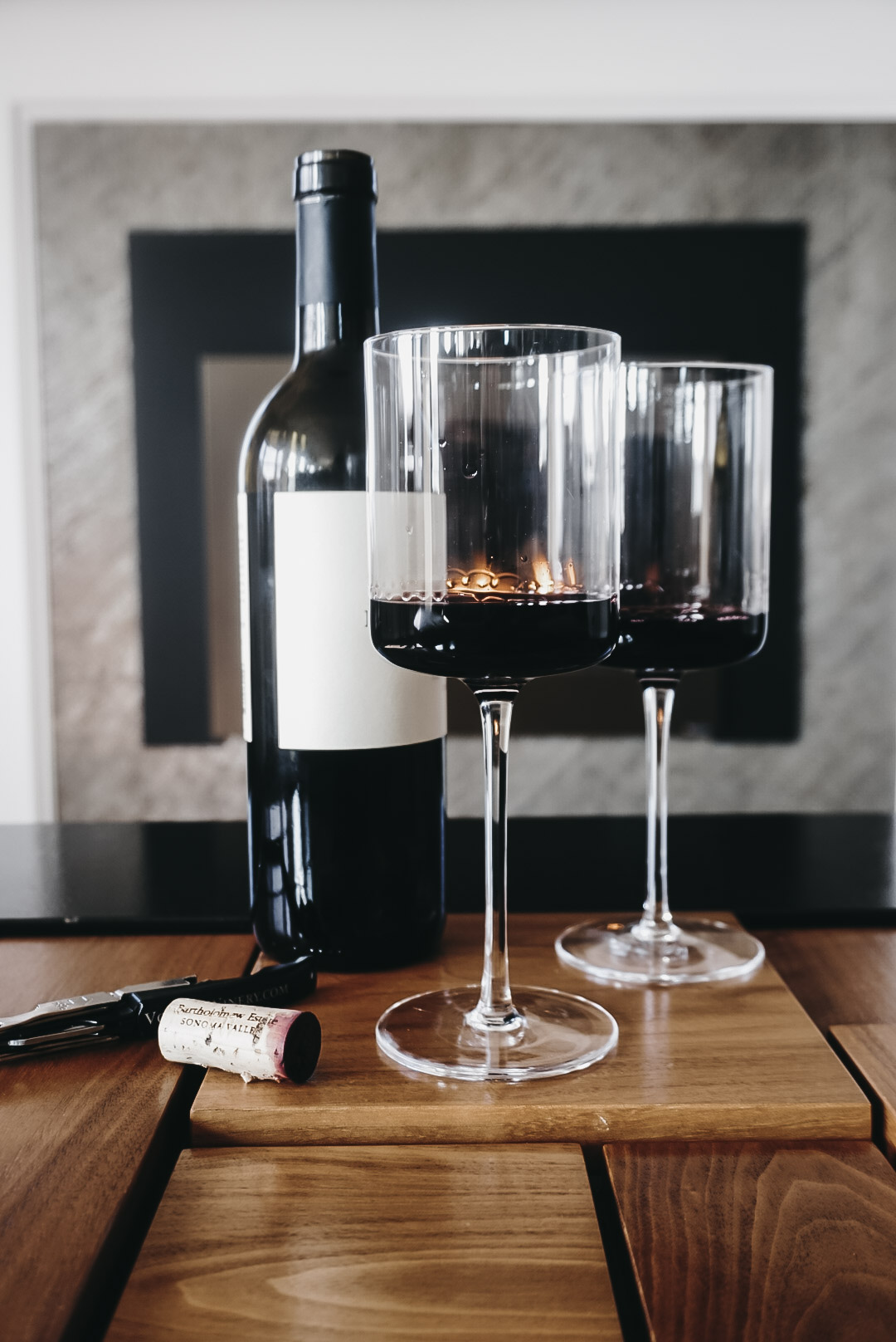 wine bottle and glasses in front of fireplace