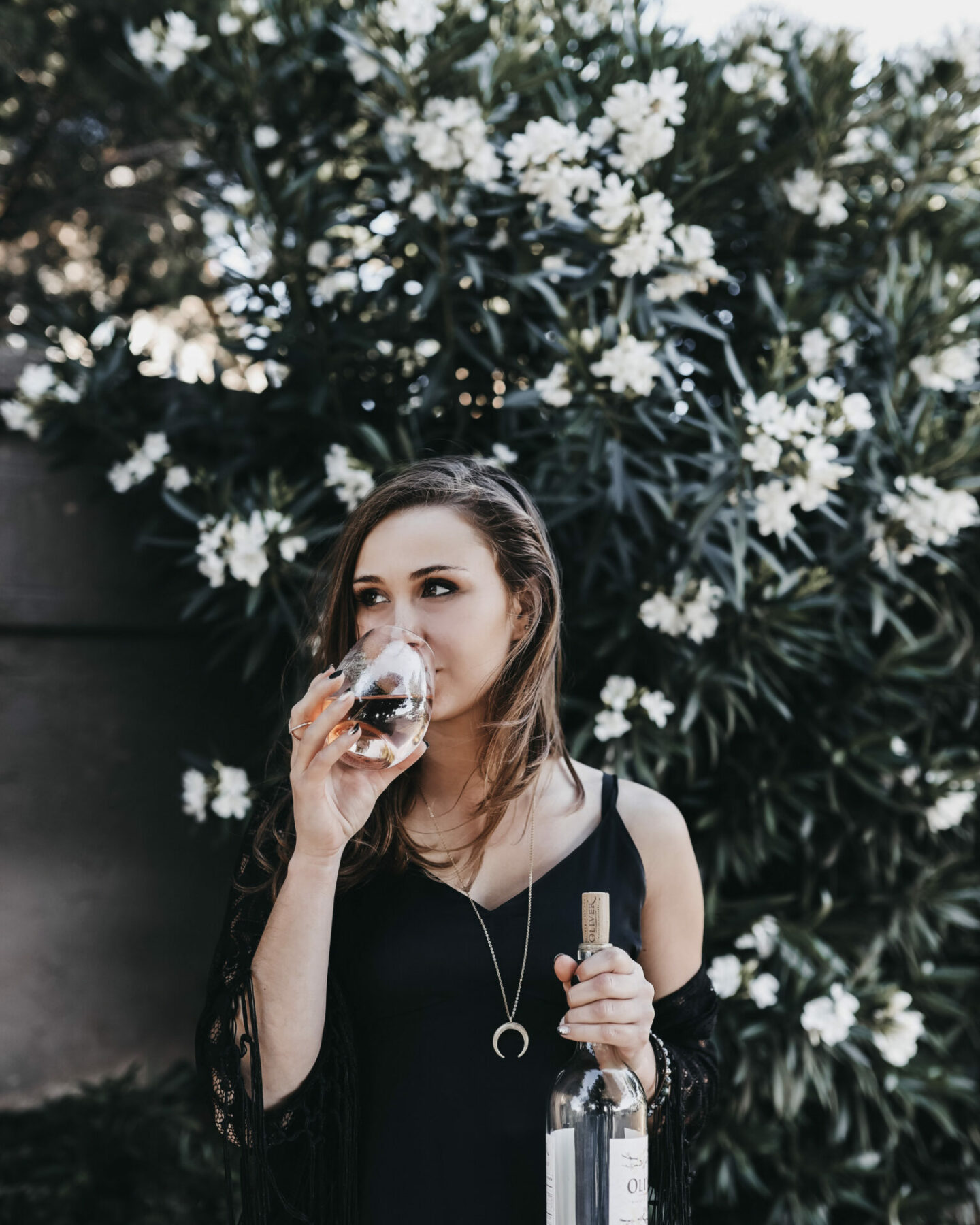 Paige sipping rose in front of flowers