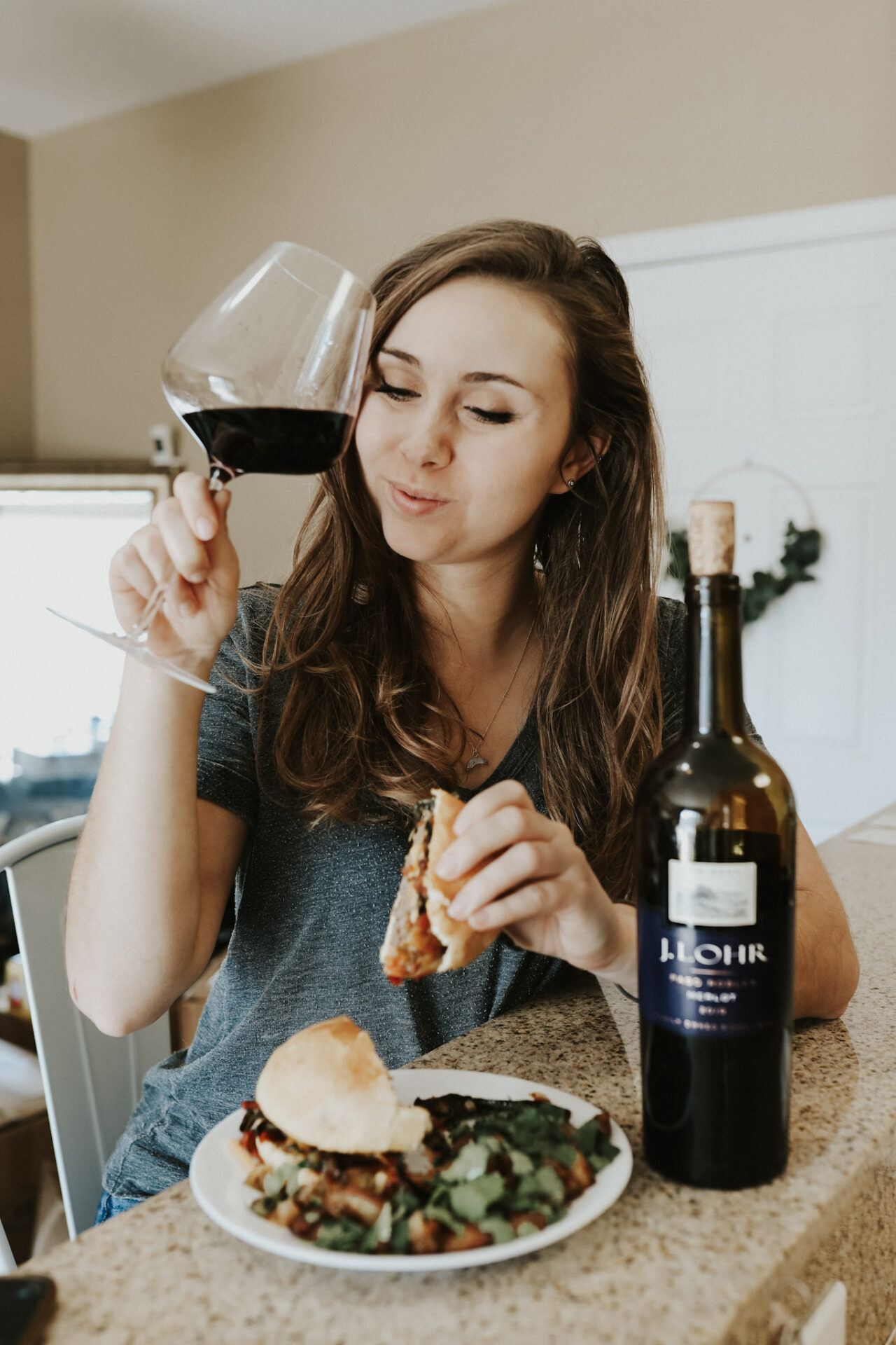 Paige drinking J. Lohr Merlot and eating BBQ Bacon Cheeseburger