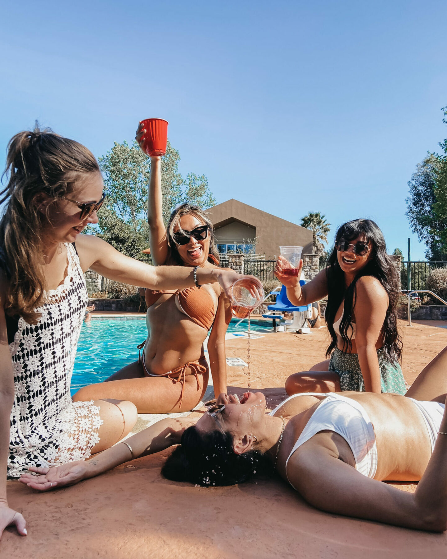group of women drinking wine by the pool