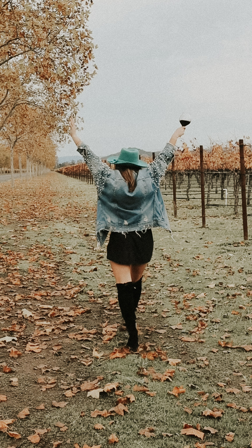 A girl posing with a glass of red wine serving as a muse for a wine Instagram caption including funny wine puns