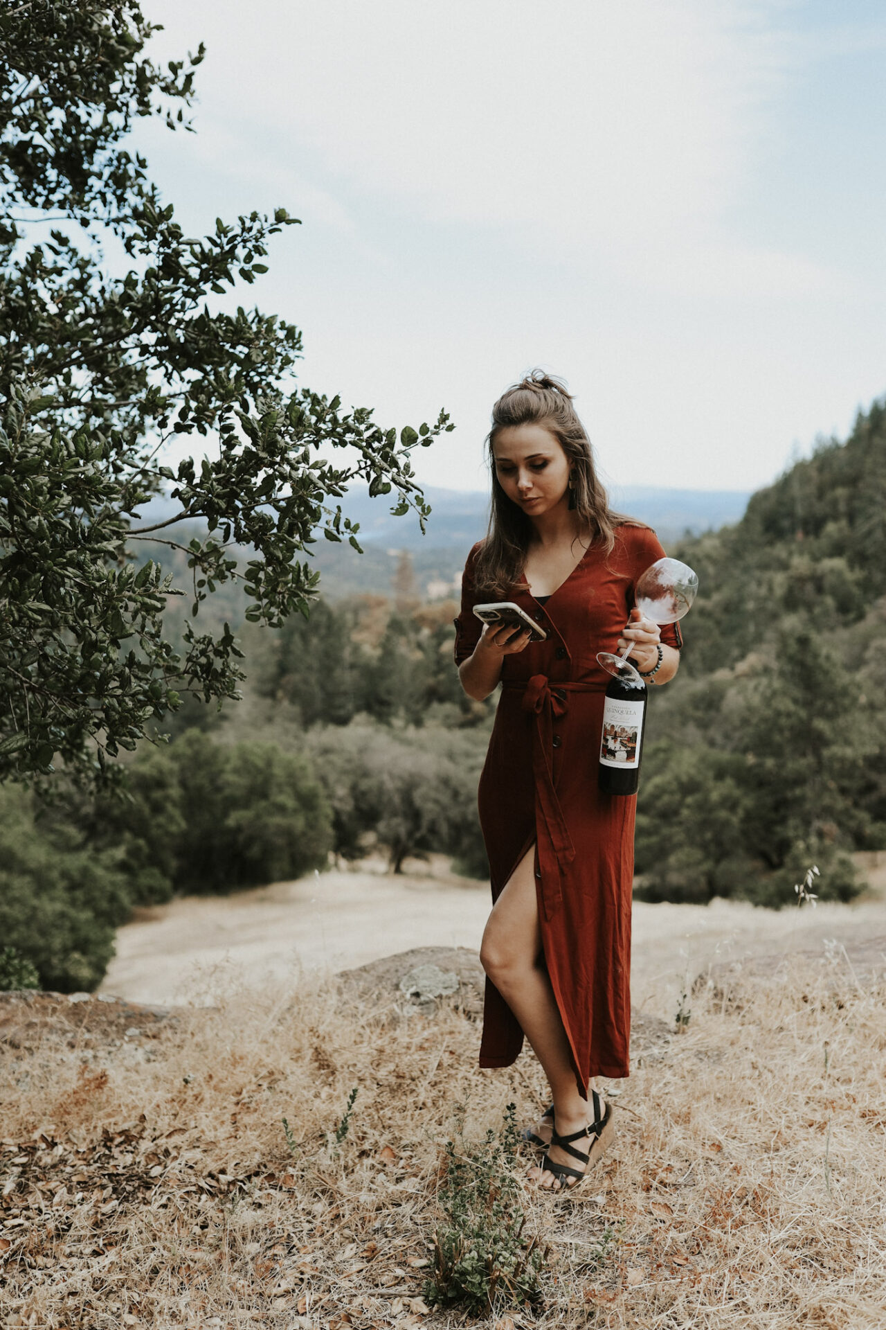 a girl holding wine bottle while on her phone writing an wine instagram caption