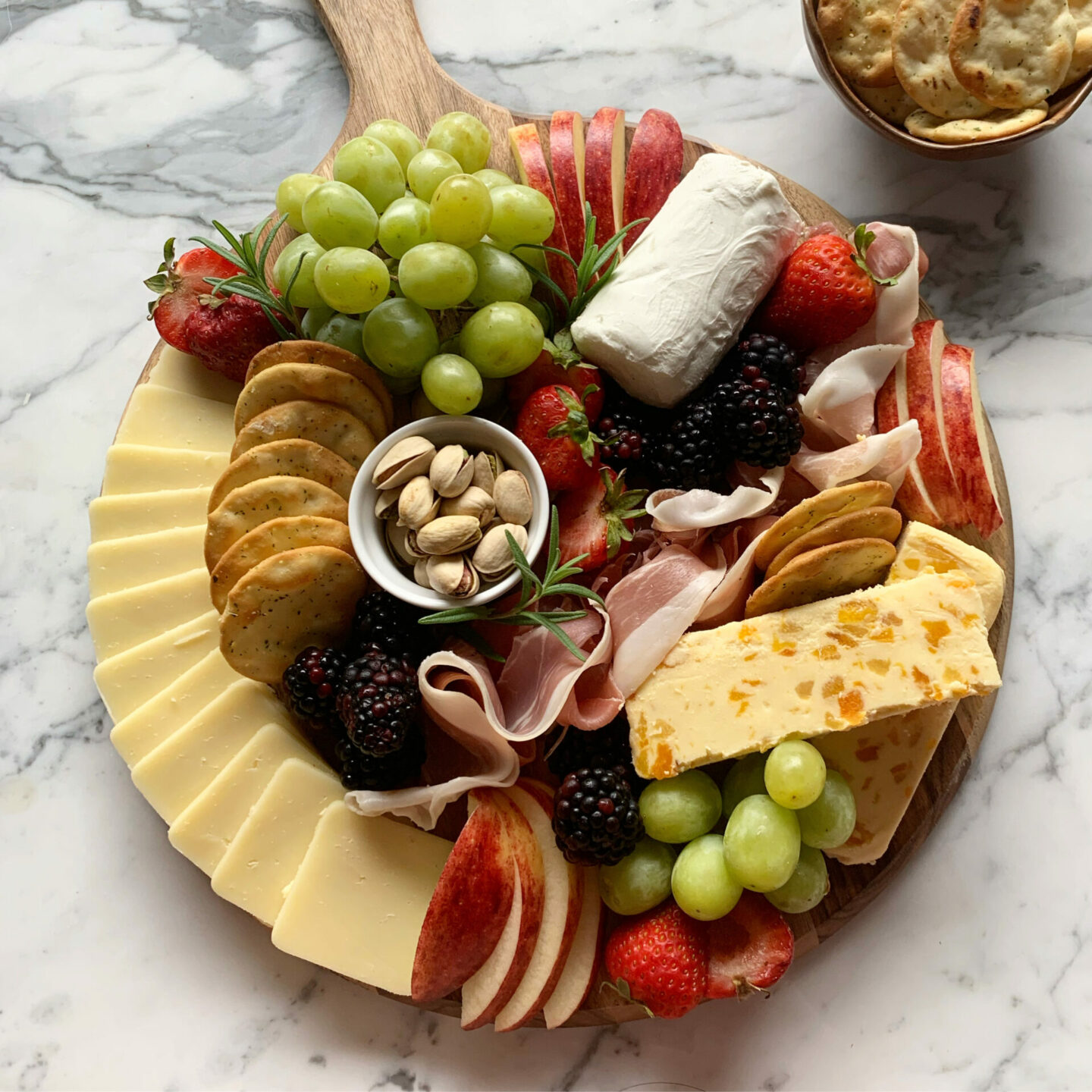Round basic charcuterie board with meat and cheese and grapes