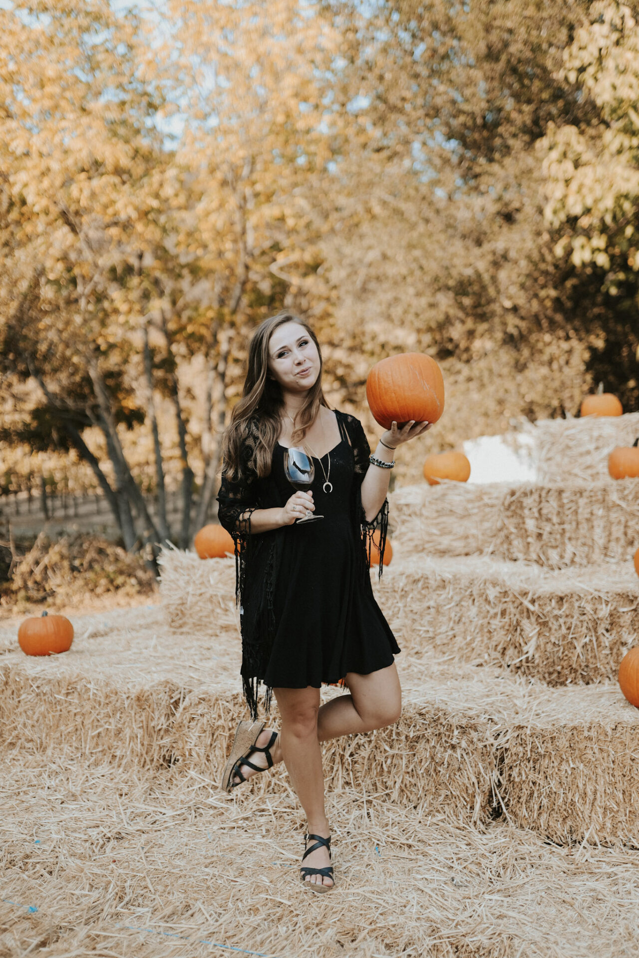 Paige holding a Halloween wine glass and pumpkin