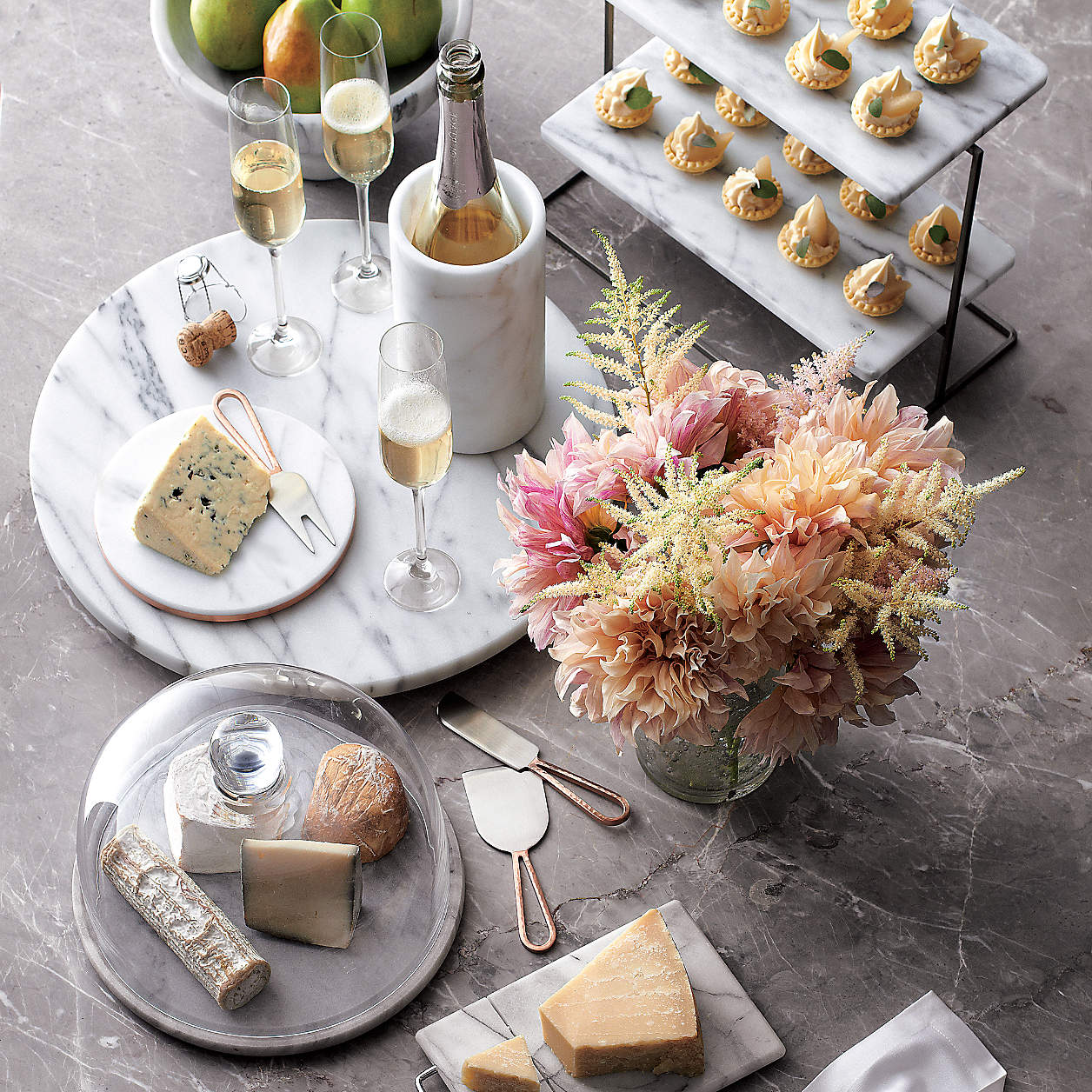 Wine chiller placed amount champagne glasses, cheeses, puff pastry and fresh cut flowers