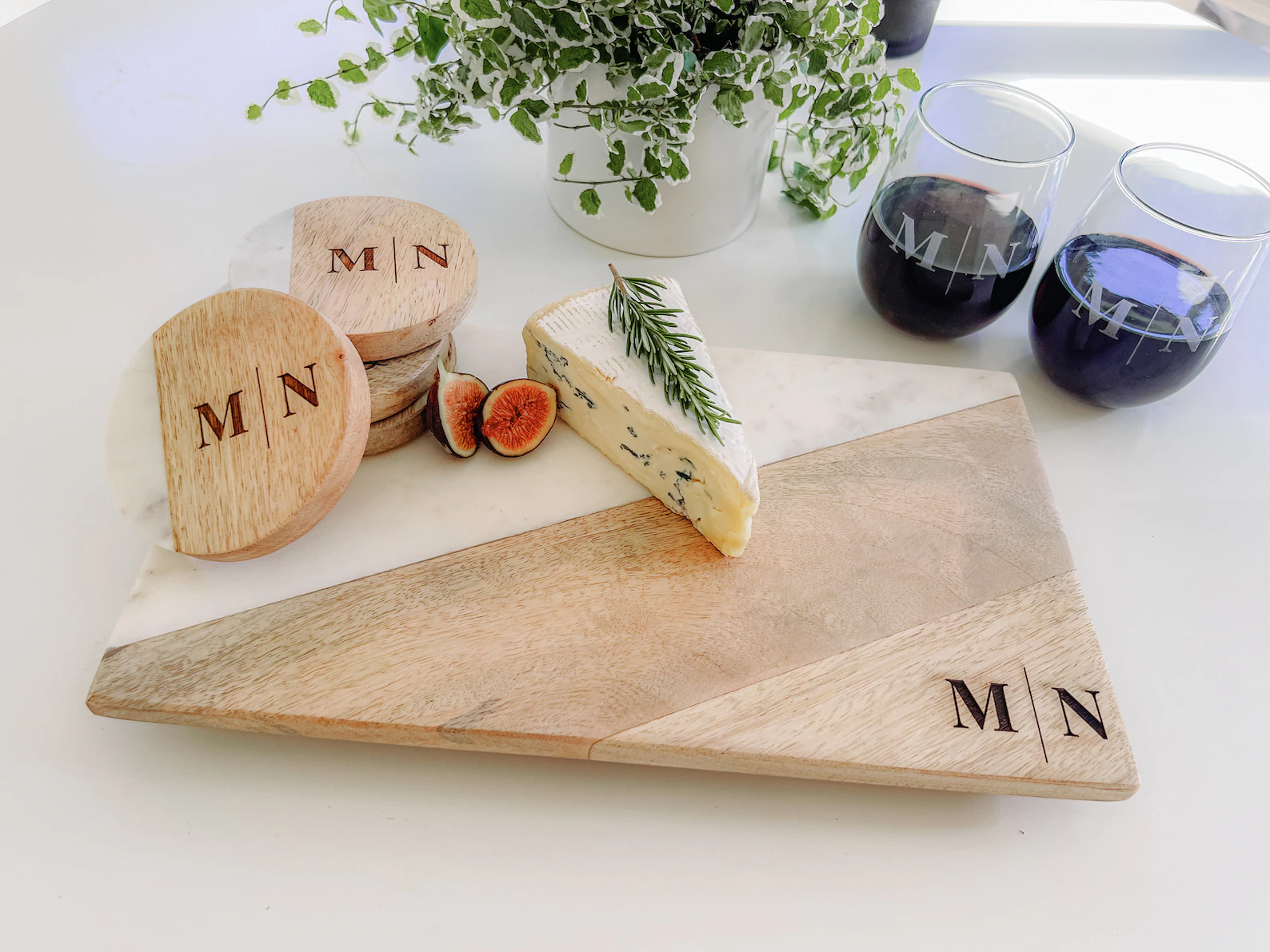 Cheese plated on personalized charcuterie board with matching coasters and wine glasses