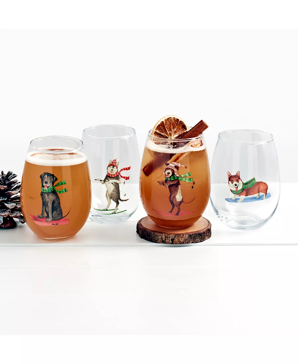 Four stemless wine glasses featuring cartoon dogs doing winter sports