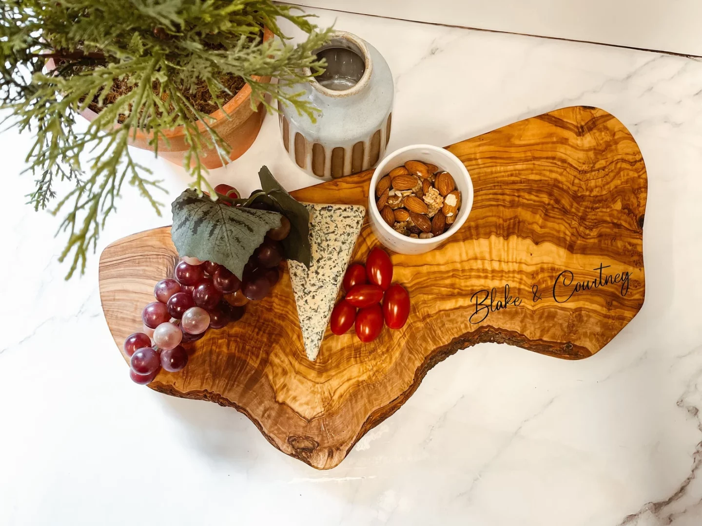 Cheese and grapes plated on a live edge, olive wood charcuterie board