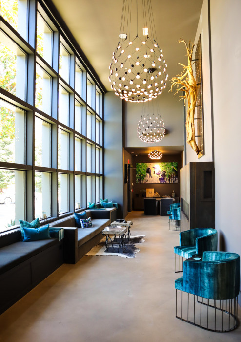 Hotel hallways with large glass windows, plush seating and statement light fixture