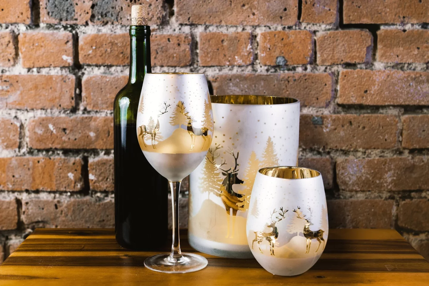 Gold and metallic wine glasses with silhouettes of reindeer and evergreens