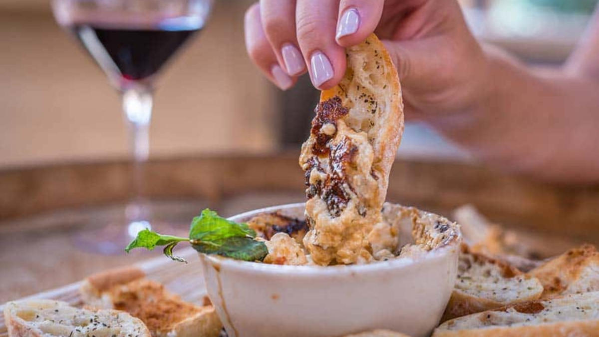 A hand pictured holding a piece of bred and dunking into a sauce