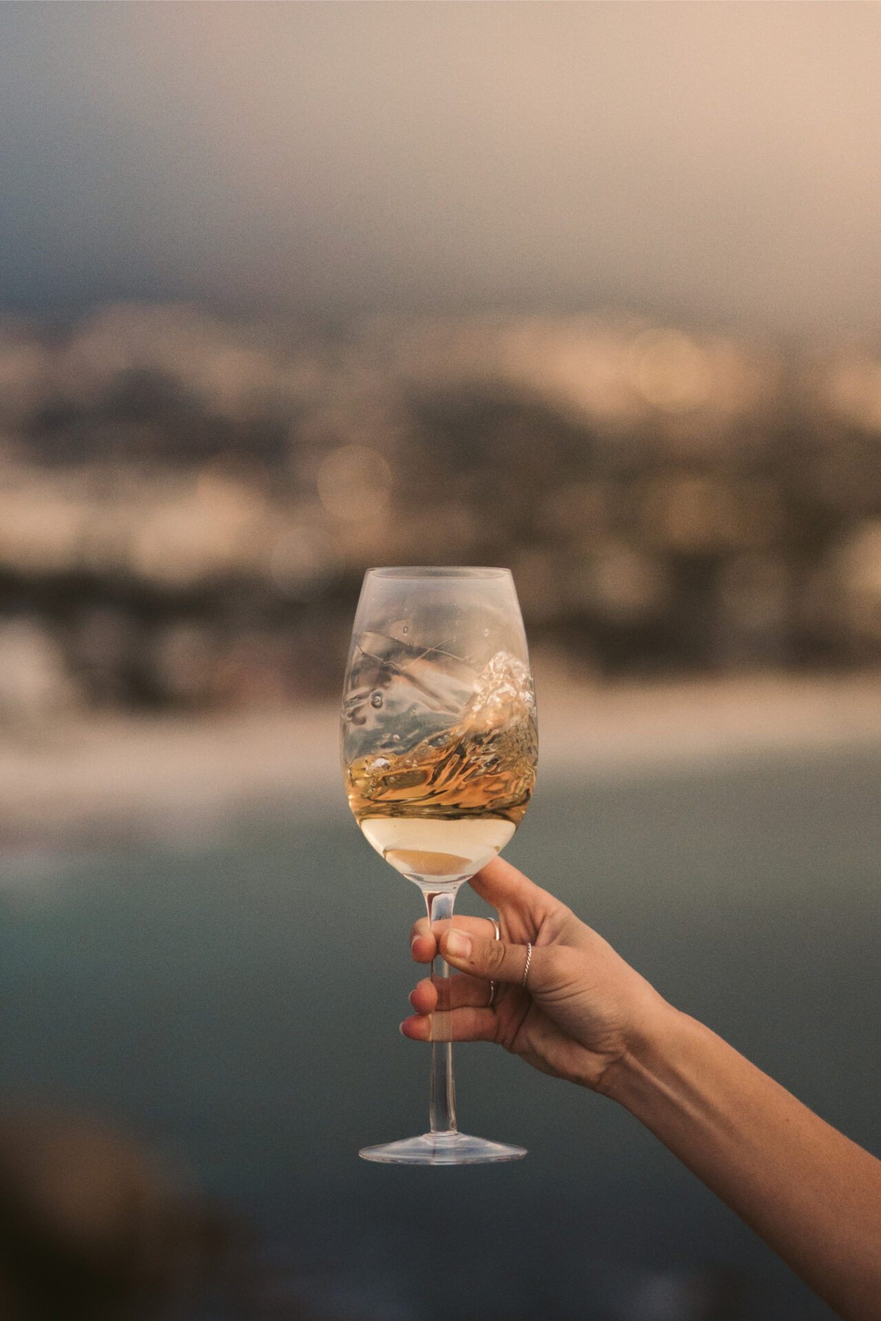 Grillo white wine in a glass in front of the ocean in Sicily