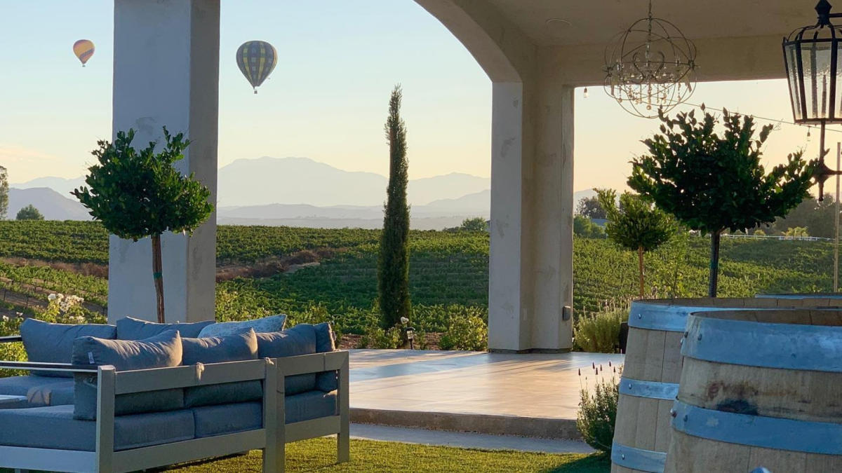 Outdoor patio overlooking vineyard and hot air balloons on horizon