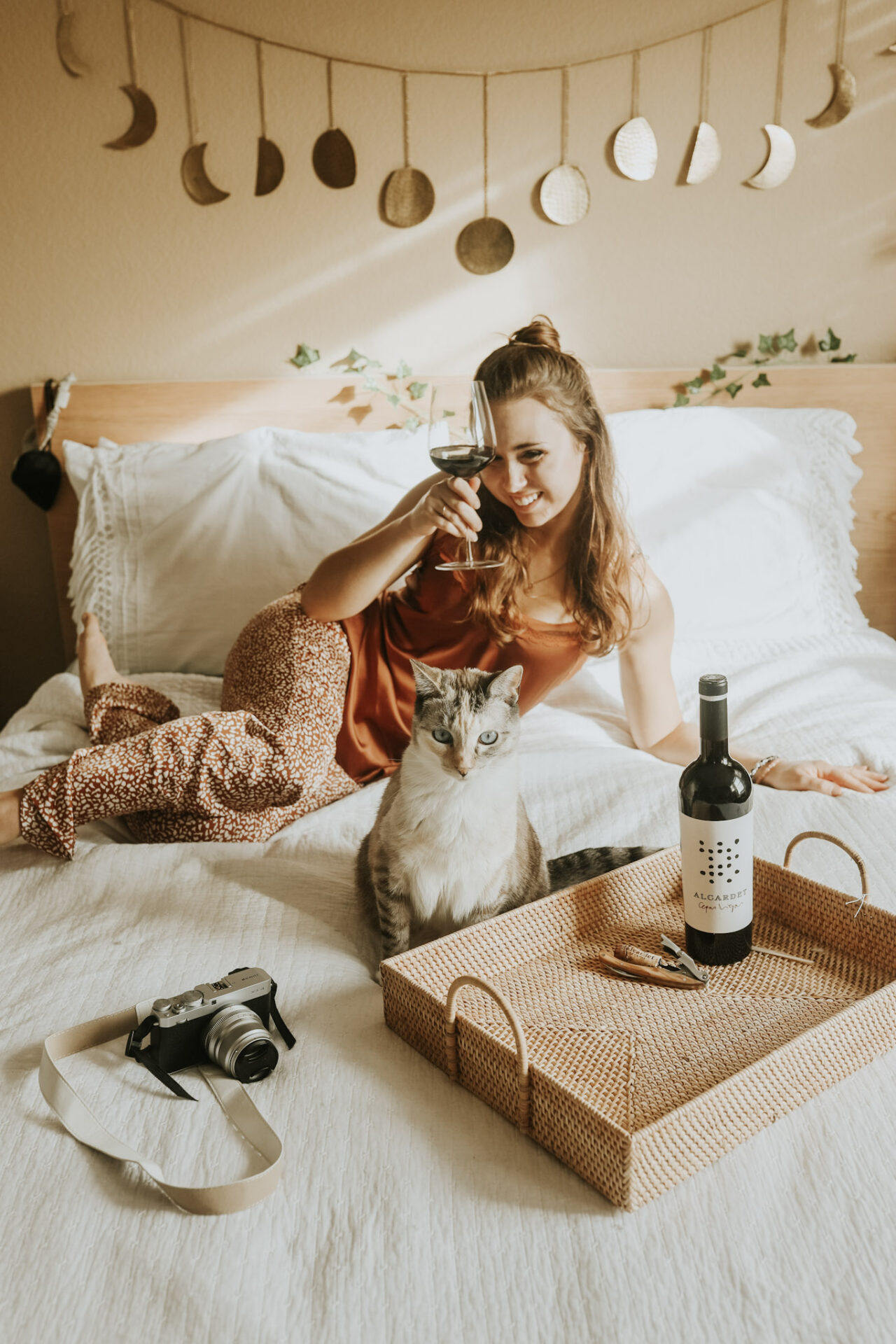 Malbec vs Merlot Wines - Paige on a white bed with red wine and her cat, Arwen. A camera is in the foreground