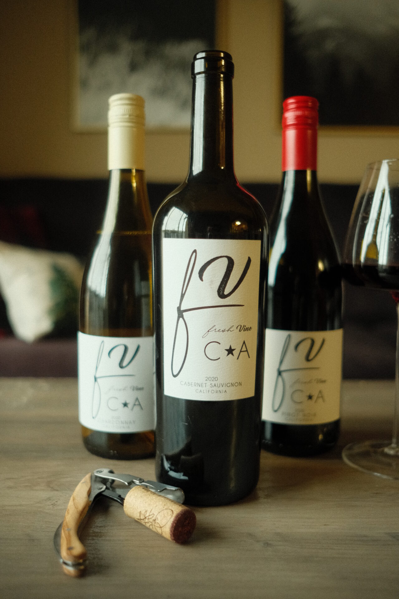 Fresh Vine Wine Review - Cabernet Sauvignon, PInot Noir, and Chardonnay wine bottles with a glass of red wine and corkscrew