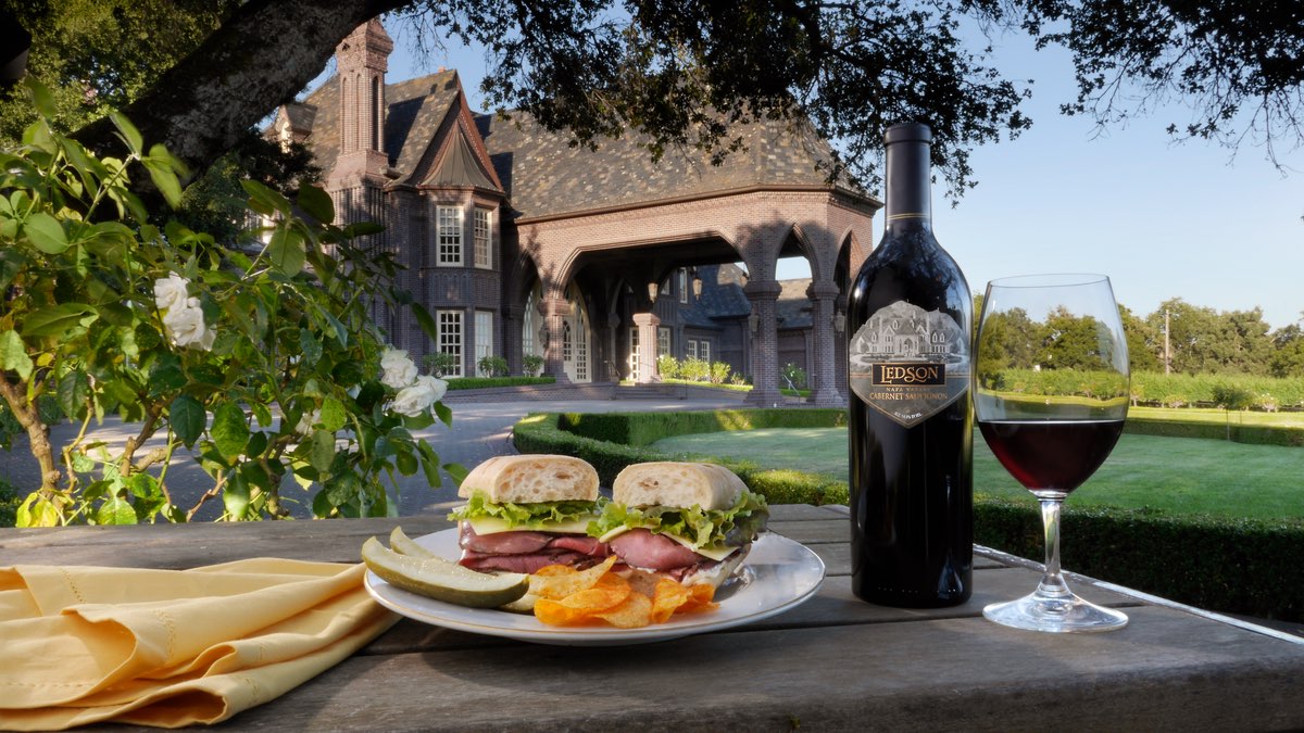 A bottle of wine and a plate of food pictured in front of a castle entrance