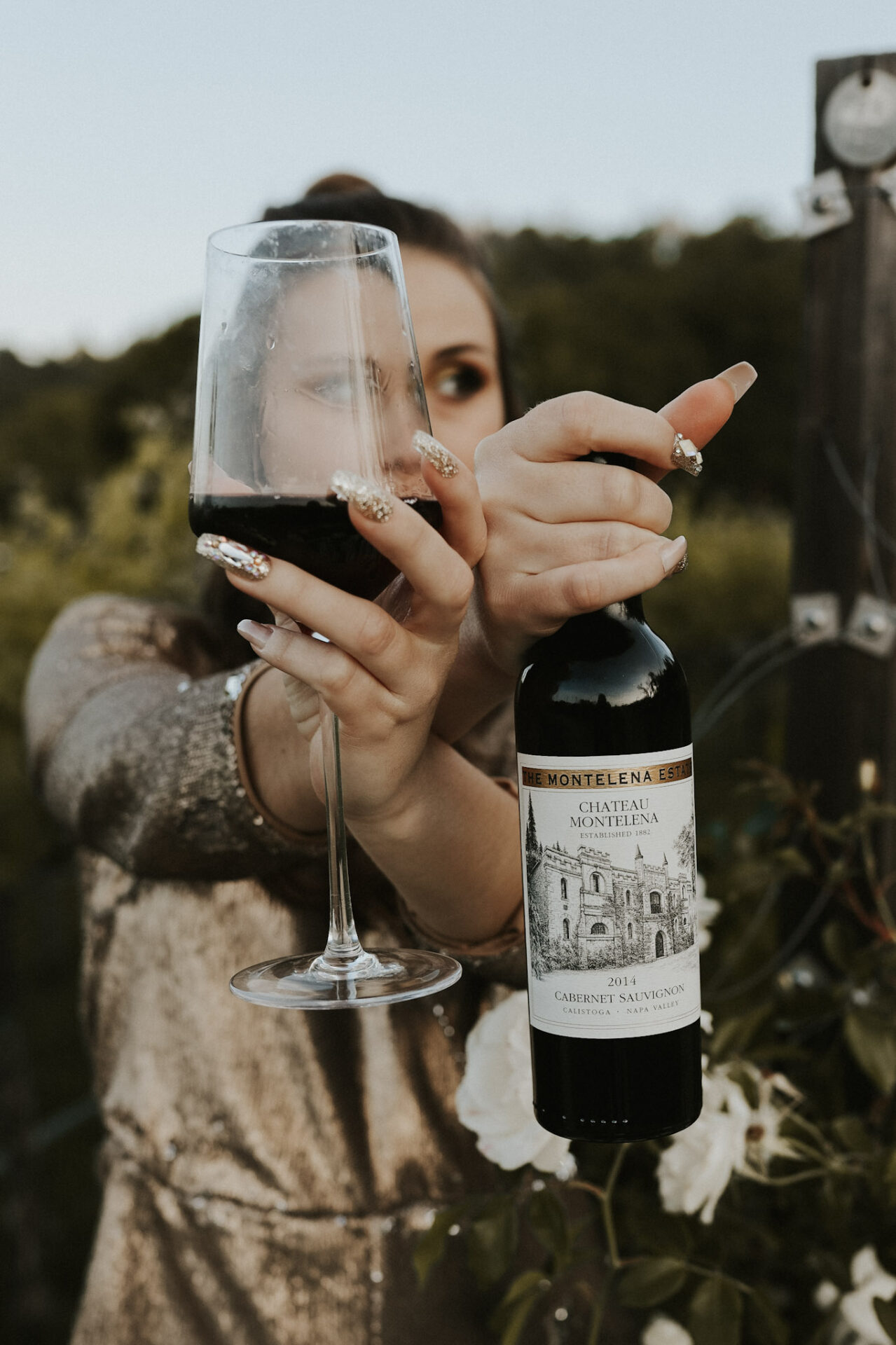 Paige posing with a bottle of Cabernet Sauvignon in a vineyard