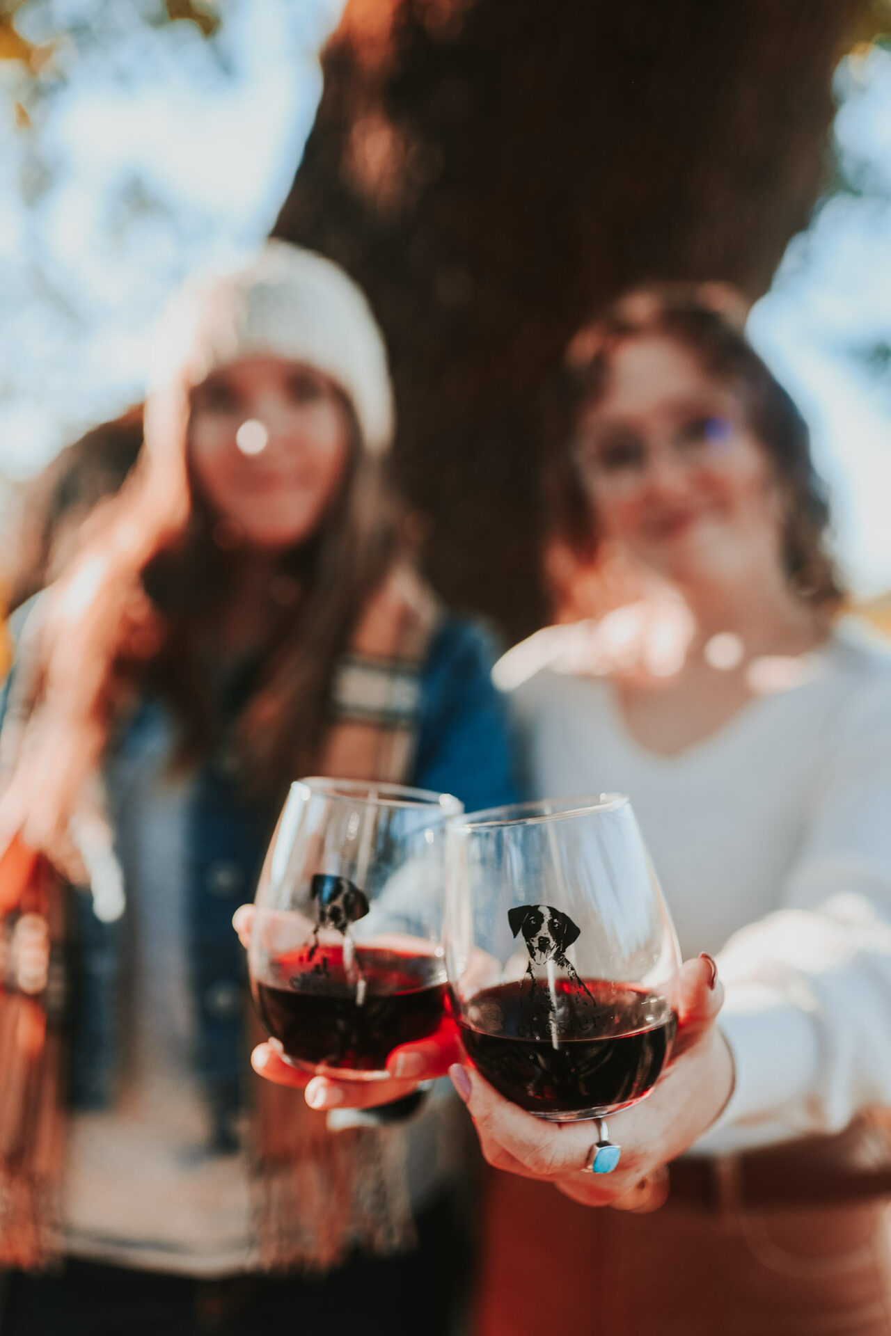 Women holding sweet red wine in stemless wine glasses with dogs on it