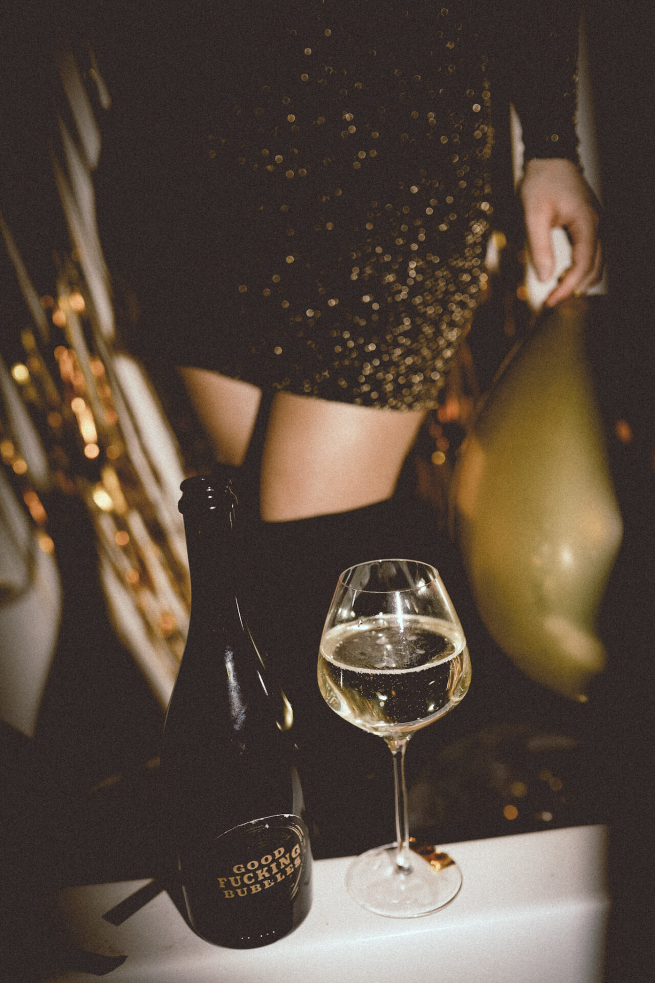 Prosecco vs Champagne - woman's legs with a glass of sparkling wine and bottle of "good bubbles"