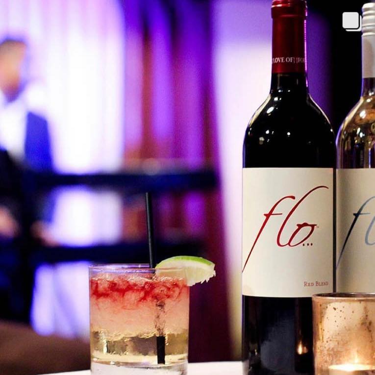 Two bottles of FLO Wine photographed with Marcus Johnson in the background