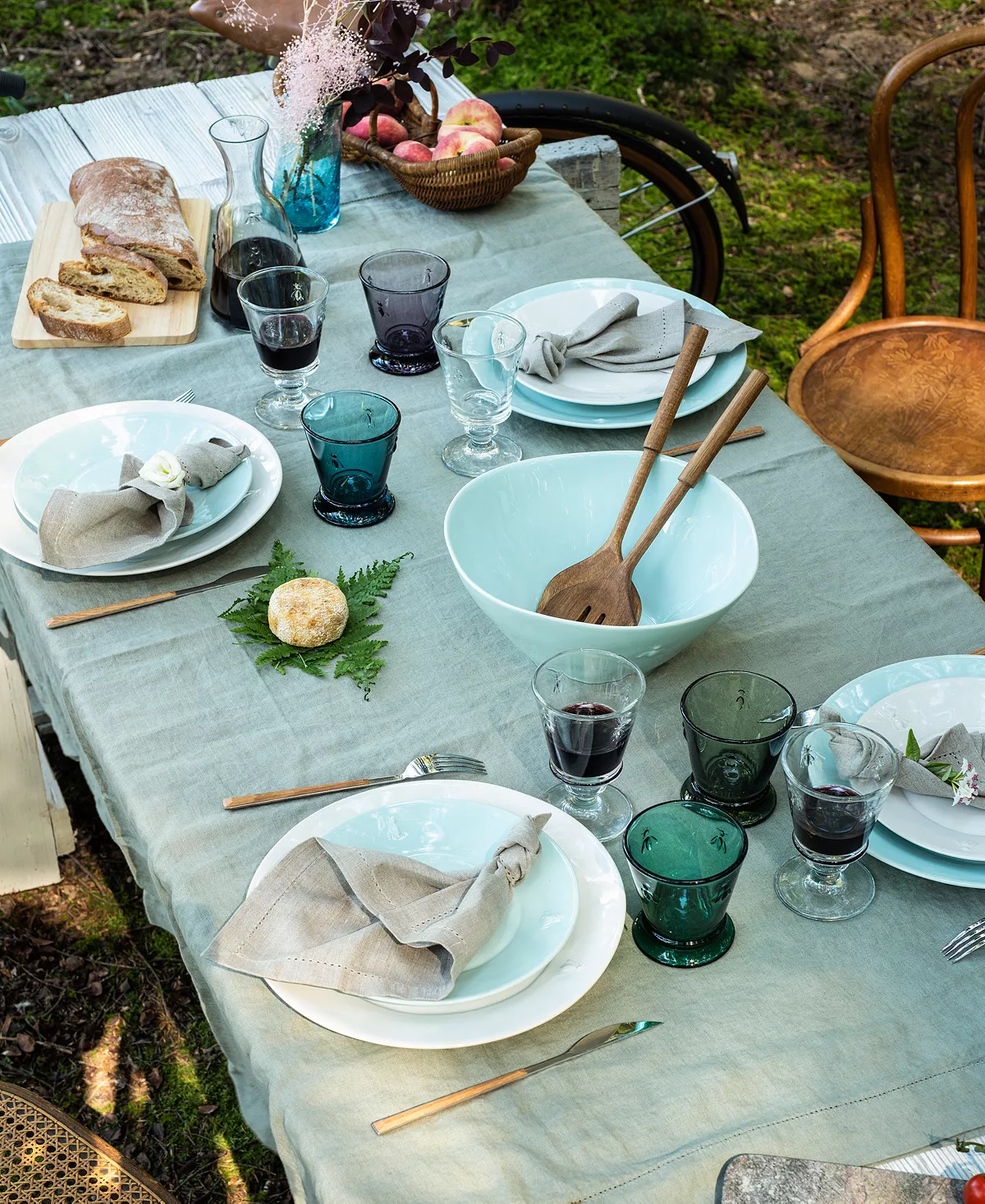 Outdoor dining table lined with place settings and various wine glasses