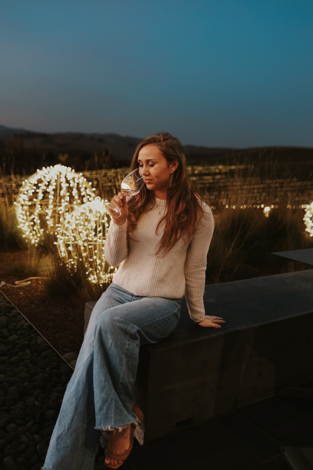 Paige drinking white wine outside after dark