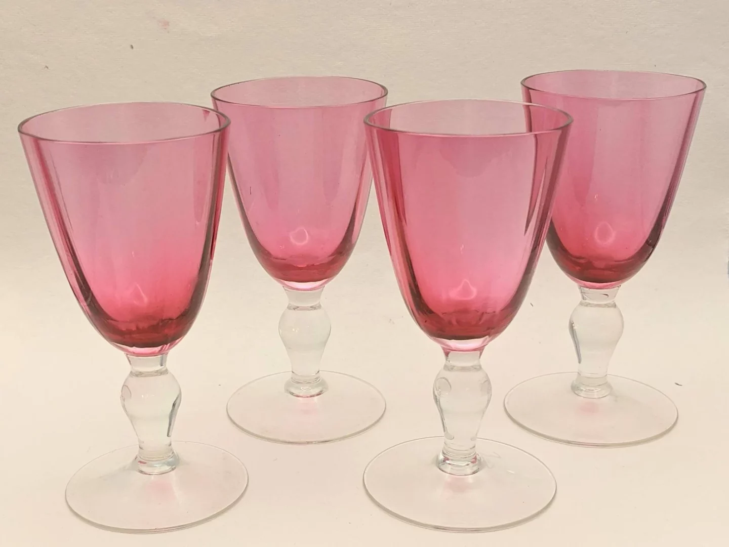 Four, cherry wine colored port glasses with a clear base