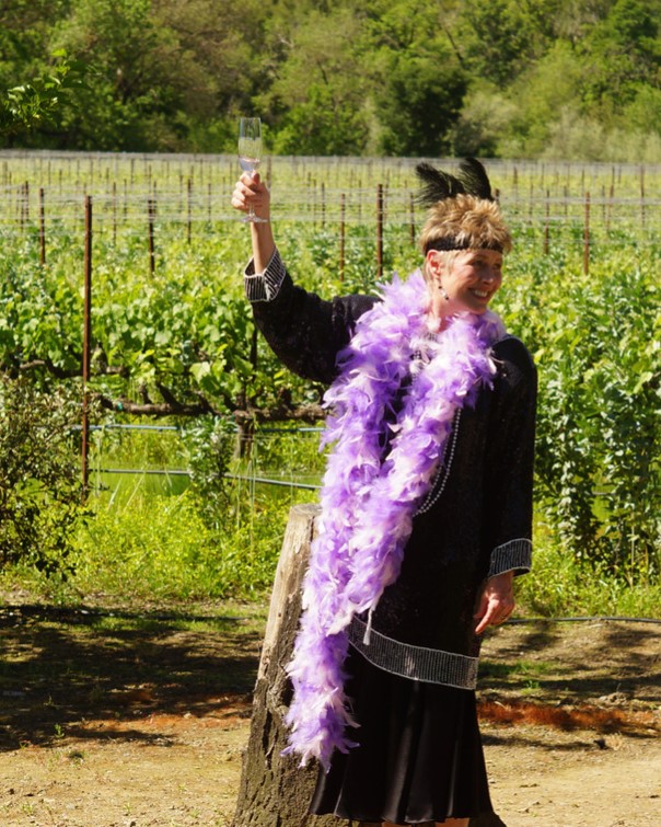 Vicky Farrow in a vineyard dressed with a purple feather boa