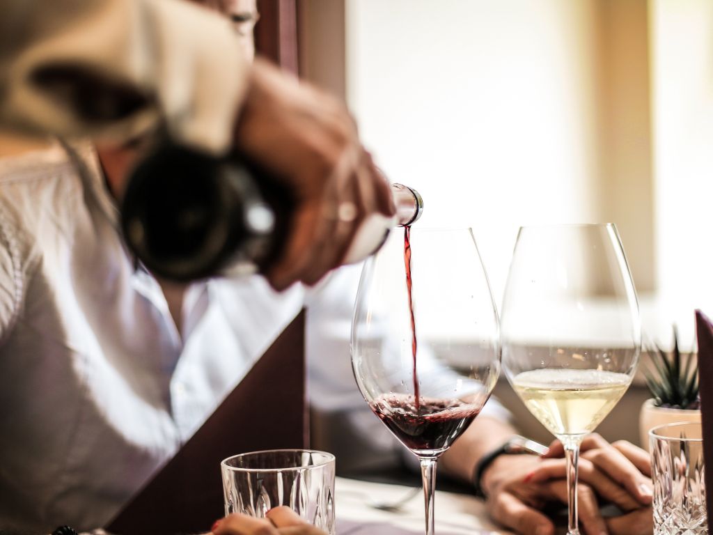 Man pouring Nerello Mascalese into a glass next to a white wine glass