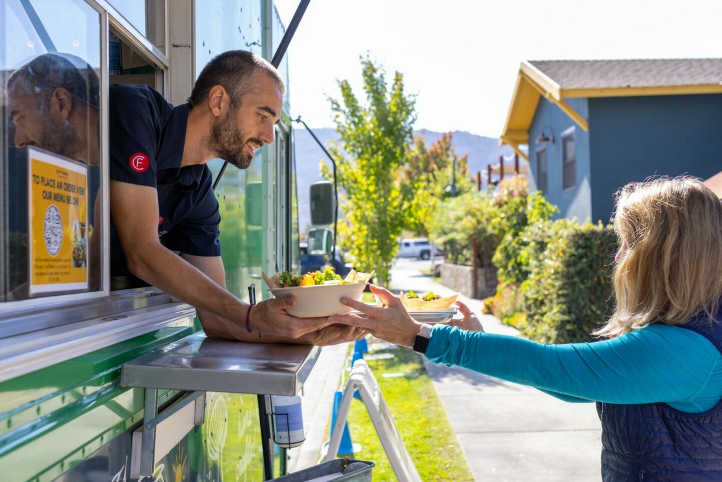 Man handing a food truck order out the window to a woman in St Helena, CA