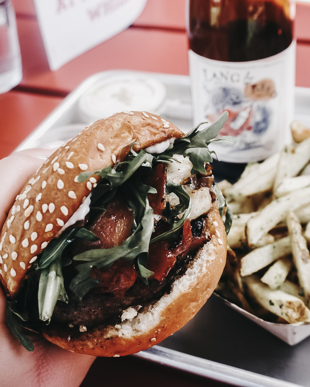 Burger and fries being enjoyed with a bottle of red wine outside Gott's Roadside