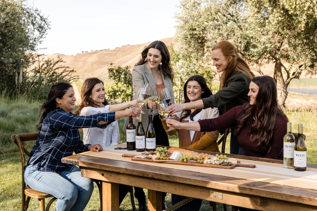 A group of women sit at an outdoor table in the middle of the vineyards at Wente Vineyards, in Livermore, CA