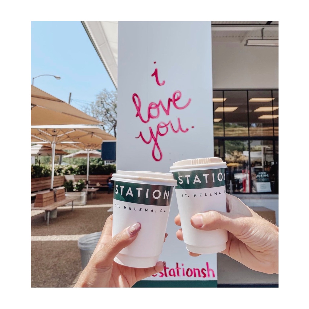 Two hands holding coffee cups outside the Station