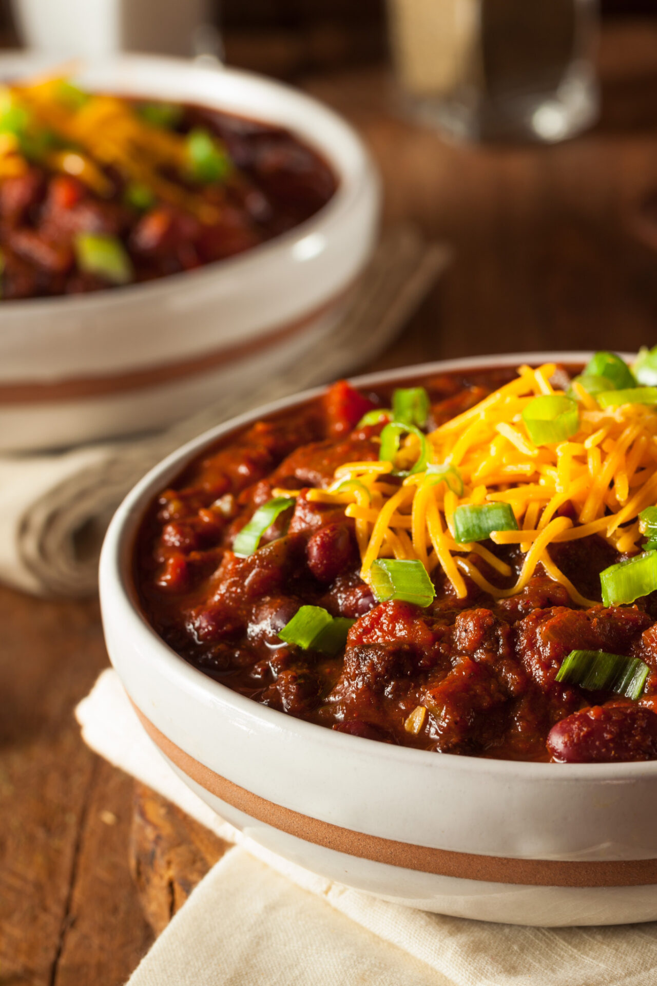 Best Wine with Chili - two bowls of chili on a table with cheese on top