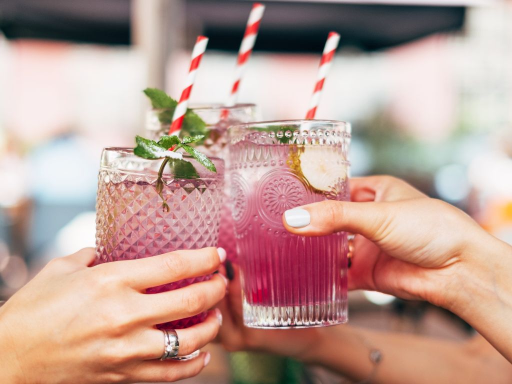 Cocktail puns for Instagram captions - three hands holding cocktails in glasses with straws