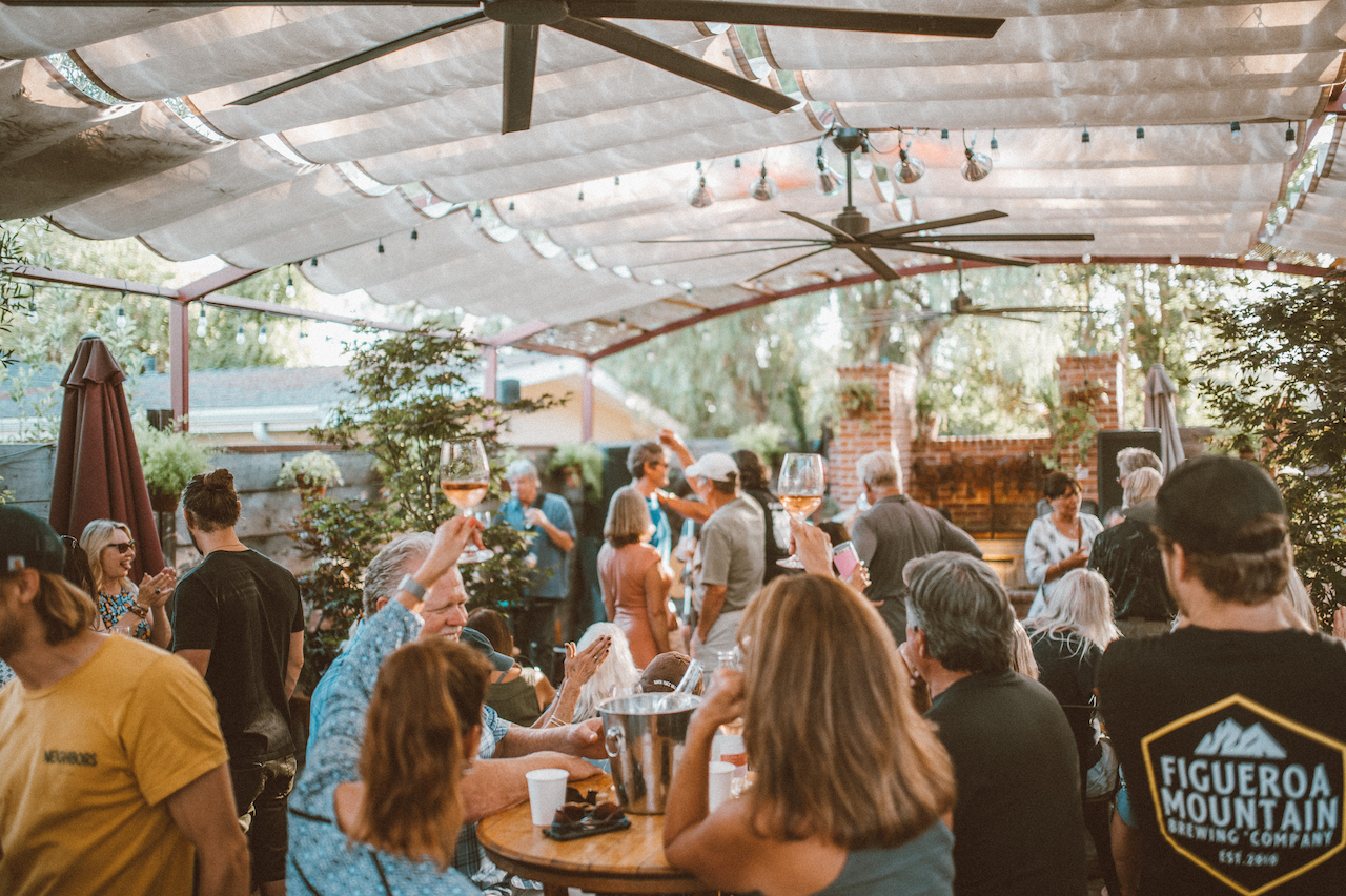 People enjoy Carhartt Family Wines while sitting under a covered outdoor patio