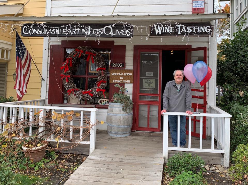 Man standing on the porch of Los Olives Tasting Room and Wine Shop