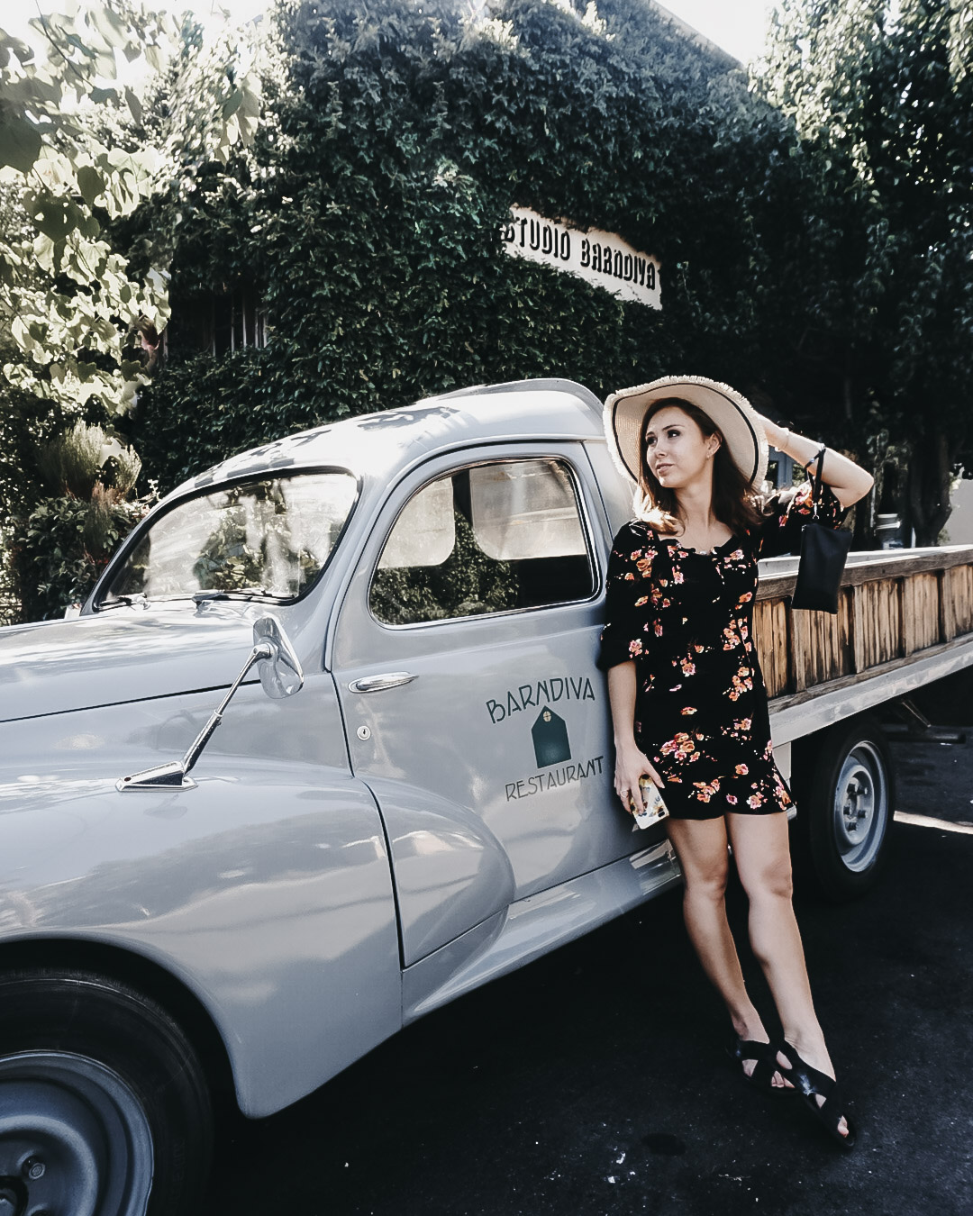 Paige leaning up against a blue pick up truck outside Barndiva in Healdsburg, CA