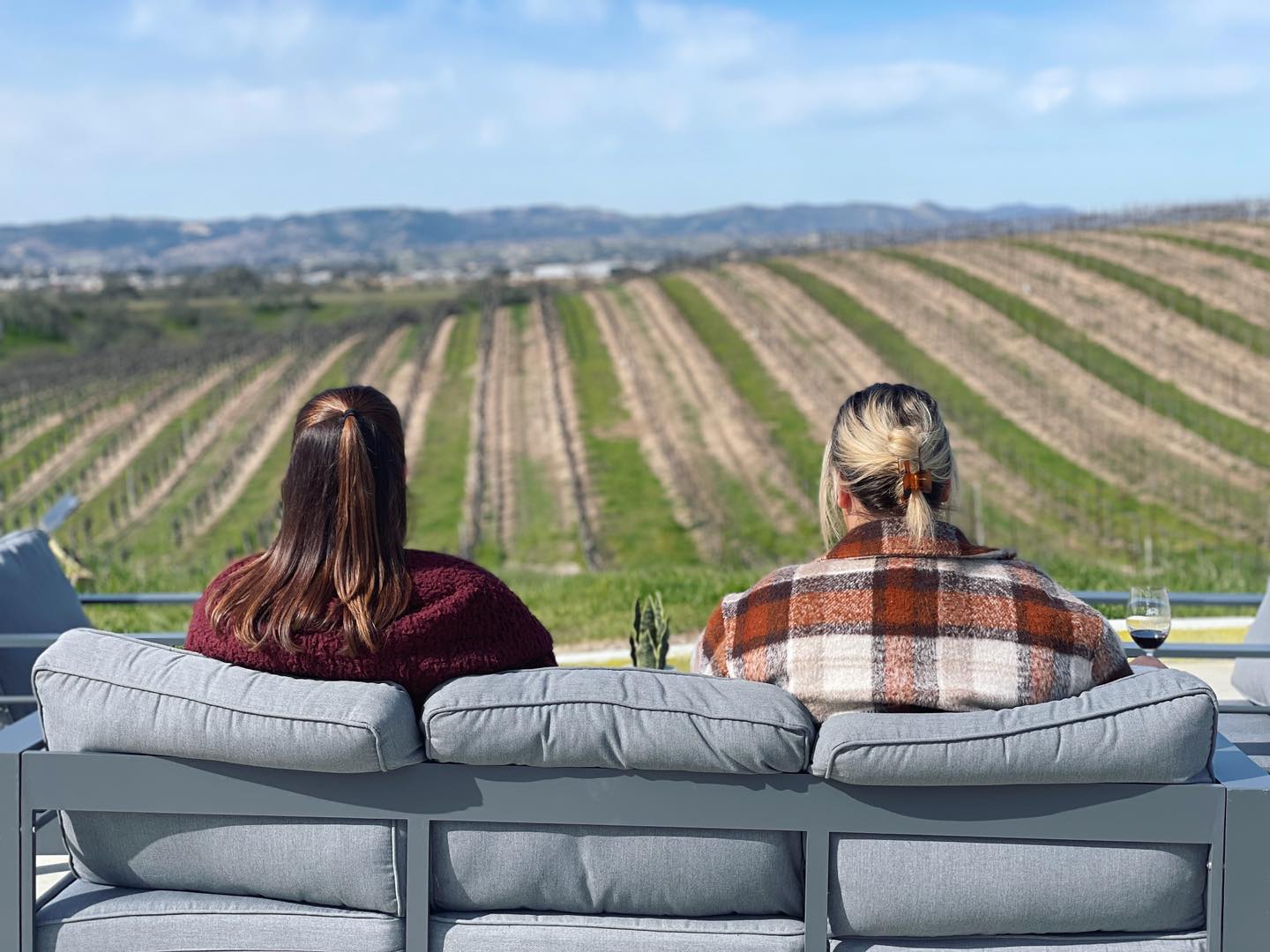 Two women sitting on the patio overlooking the vineyards of Eberle Winery