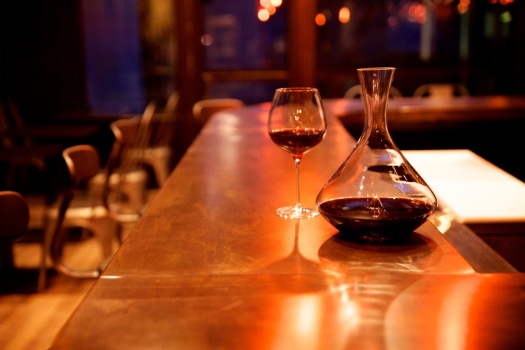 Empty wine bar with a single glass of wine and a decanter