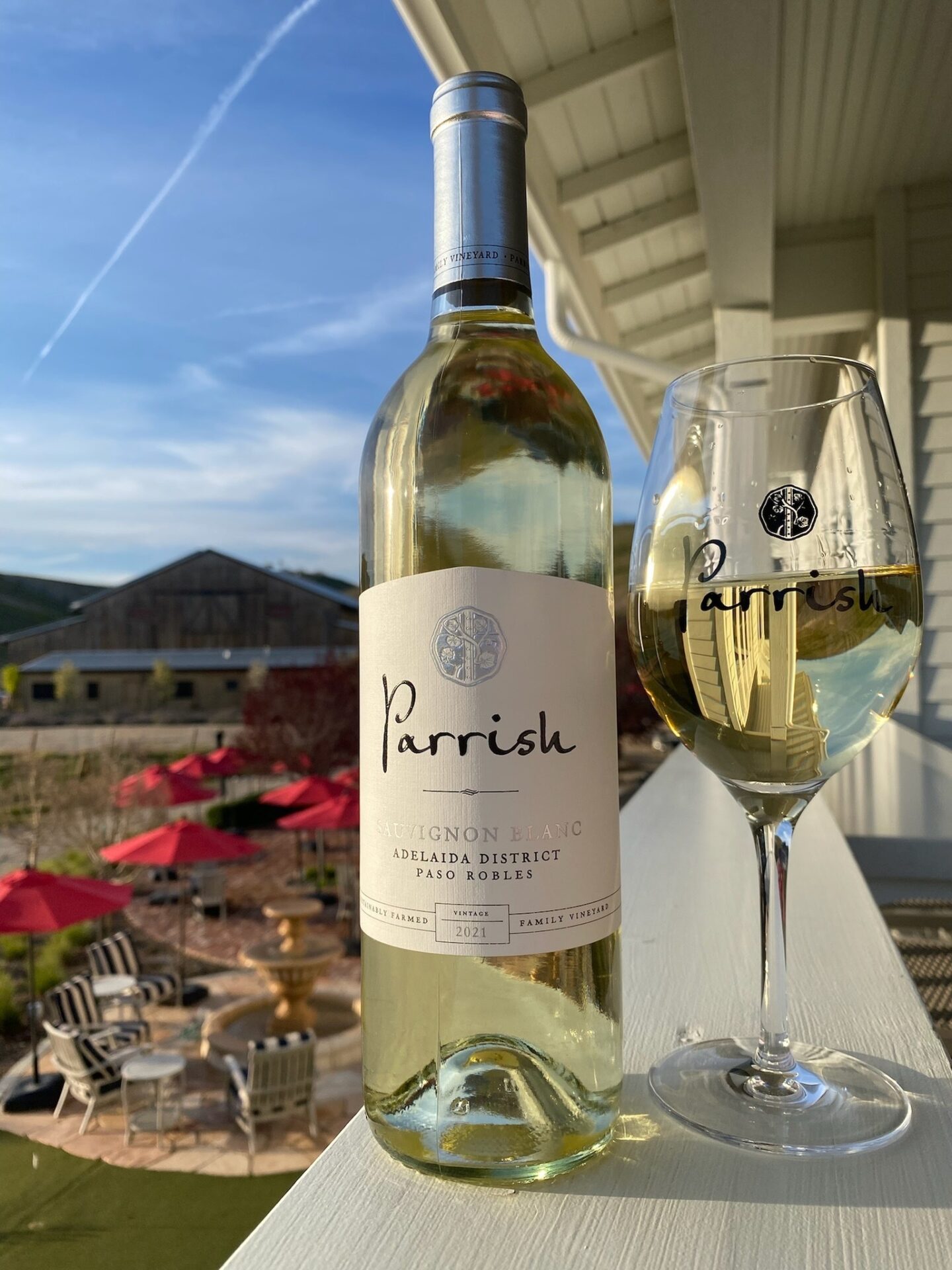 Bottle of white wine from Parrish Family Vineyard sitting on porch railing overlooking outdoor patio