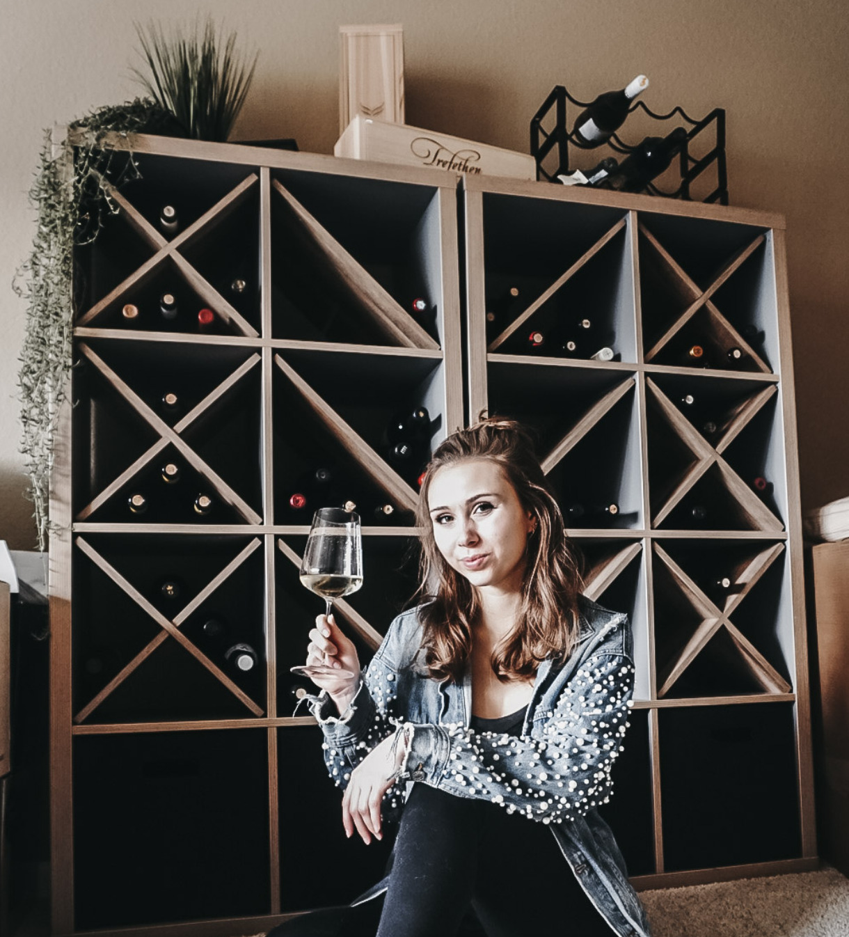 Paige poses with a glass of wine in front of her IKEA Wine Rack Hack