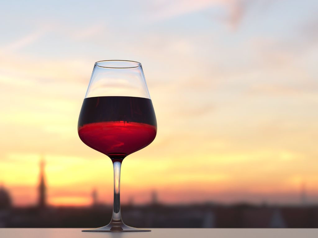Light red wine in front of a city skyline at sunset
