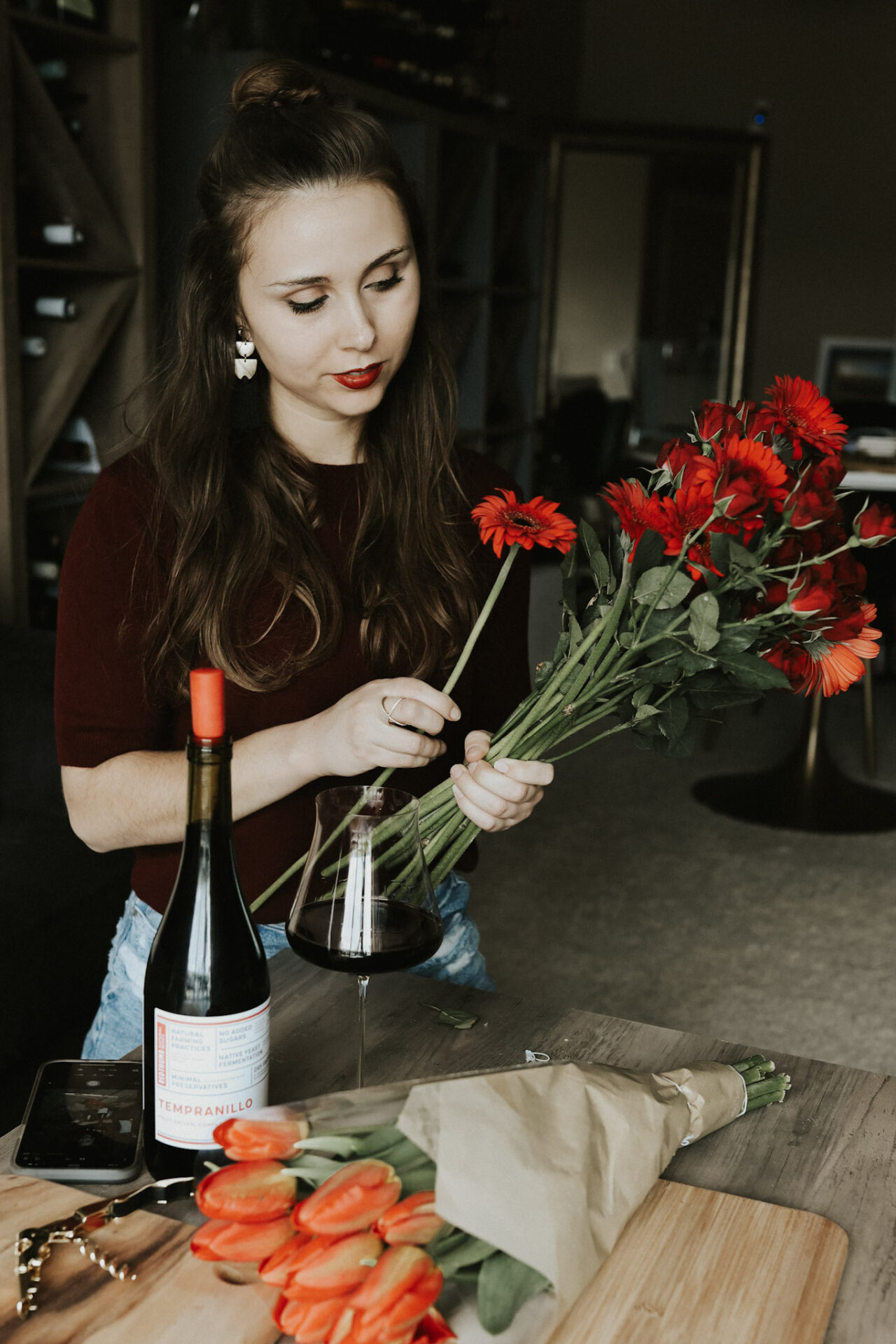 Paige with red flowers and light red wine in a glass next to her