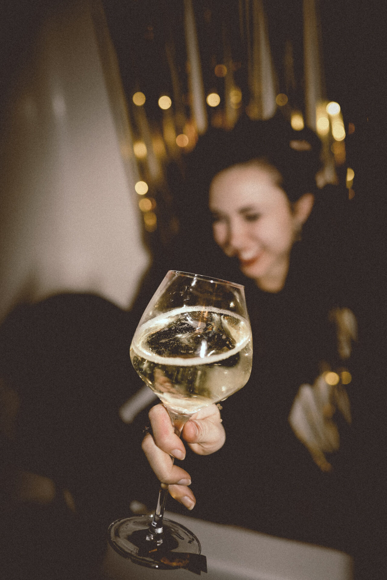 Woman holding her hand out with a glass of Blanc de Blanc Champagne
