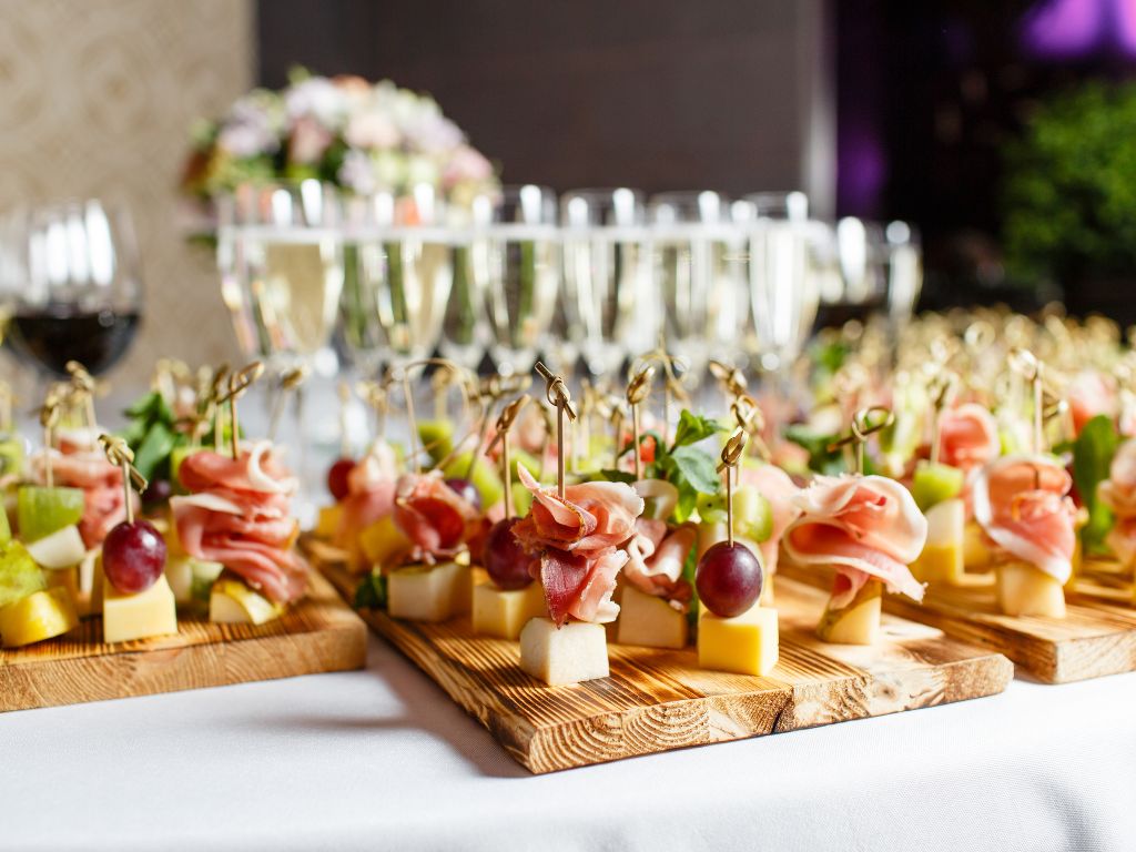 Prosciutto, fruit, and cheese bites on a tray in front of Blanc de blanc champagne glasses
