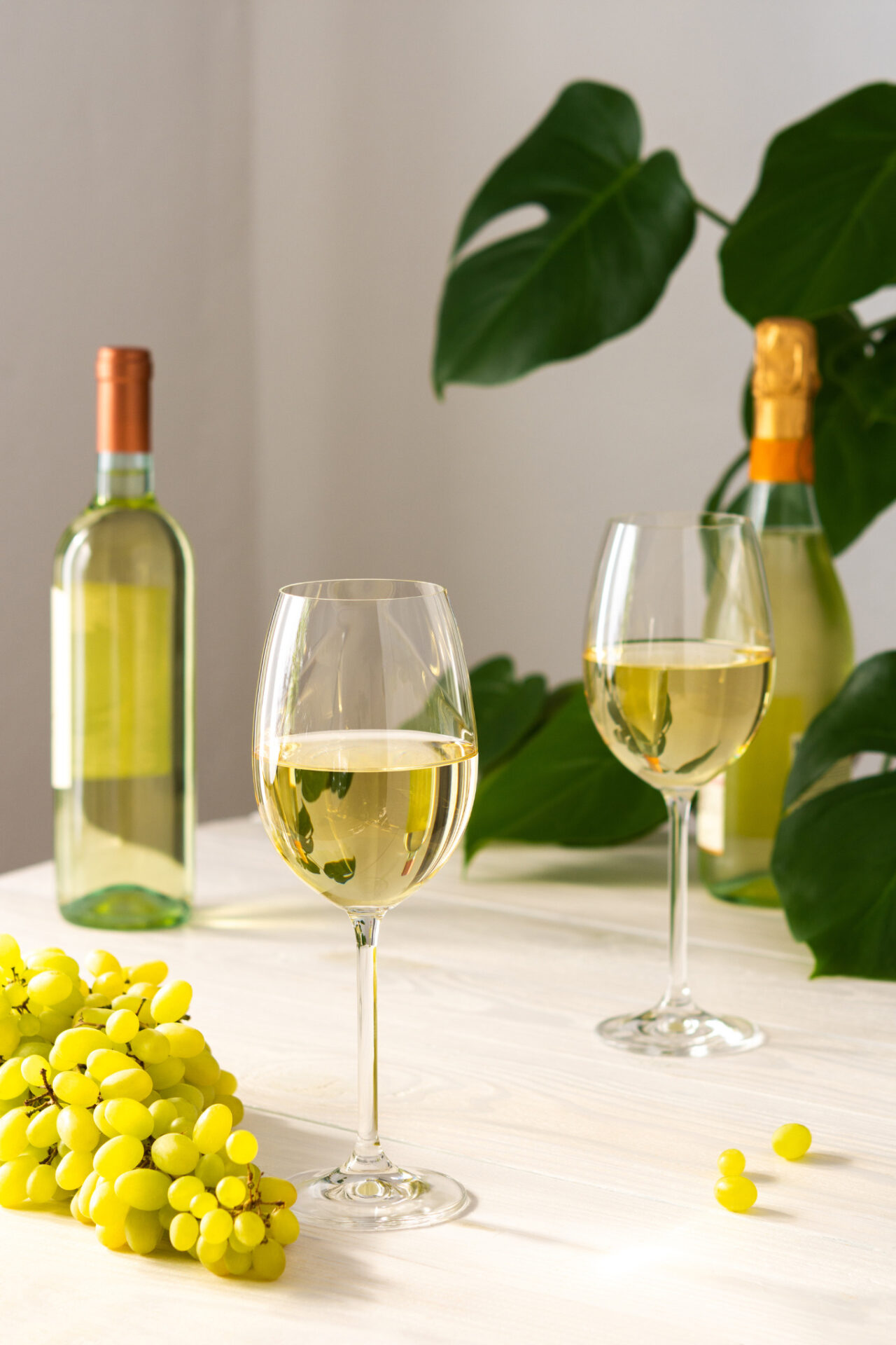 Two glasses and two bottles of Sauvignon Blanc calories with grapes on table