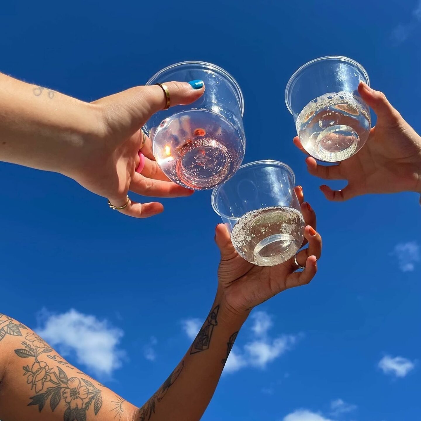 Three people cheering with stemless wine glasses made of disposable plastic